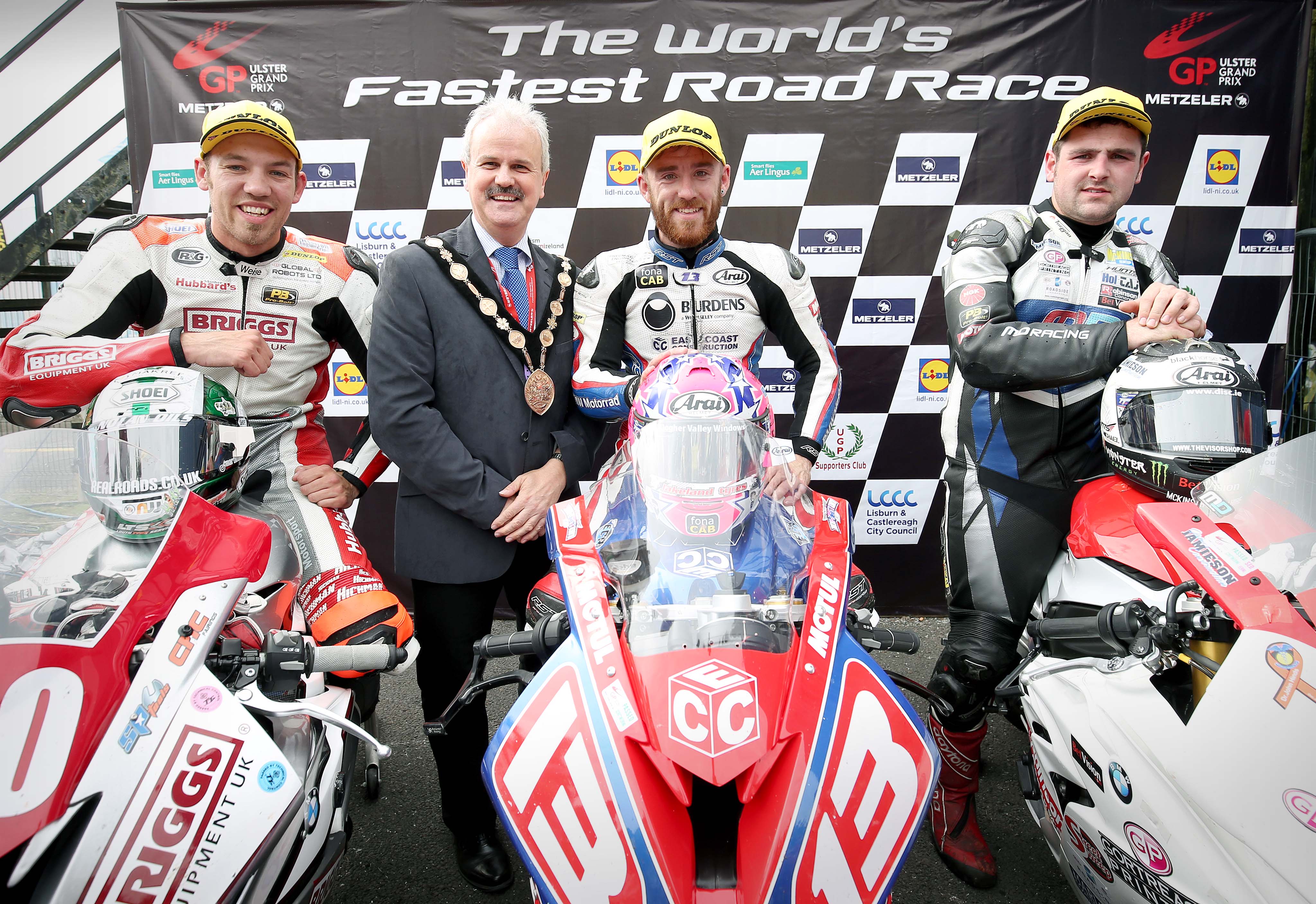 The Mayor of Lisburn & Castlereagh City Council, Councillor Thomas Beckett congratulates the top three riders in the Superstock race as they arrive back in the paddock